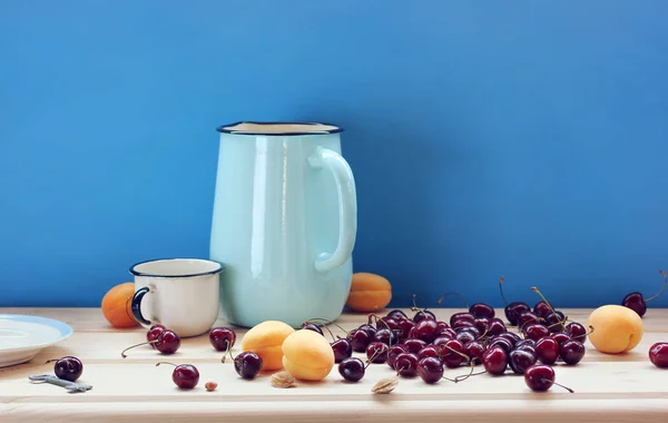 Still Life Jug Berries Table Blue Background Cherries Apricots — Stock Photo, Image