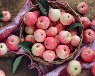 Kaba bir tabloda, üstten görünüm sepetteki rustik çizgili elma.