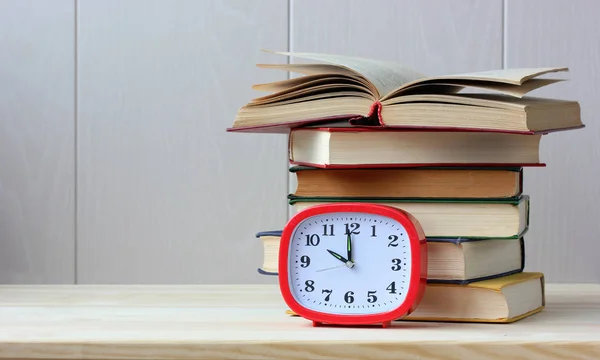 Libros y un reloj despertador de plástico rectangular rojo — Foto de Stock