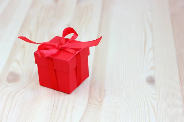 Red box with ribbon bow on wooden table, selective focus. space — Stock Photo, Image