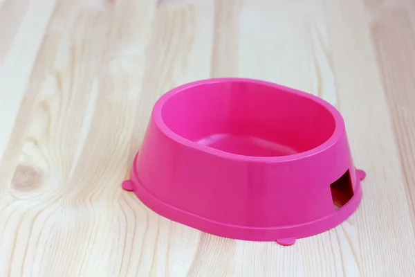 Roze plastic kom voor puppy of kitten op houten vloer. ruimte voor — Stockfoto