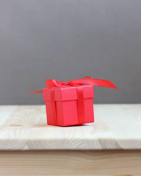 Rode doos met lint boog op houten tafel, selectieve focus. — Stockfoto