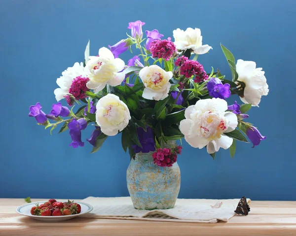 Букет садових квітів, метелик і полуниця на синій спині — стокове фото