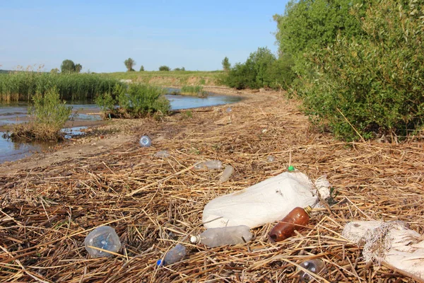 Botellas de plástico, bolsas y basura están tirados en la orilla. Residuos , —  Fotos de Stock