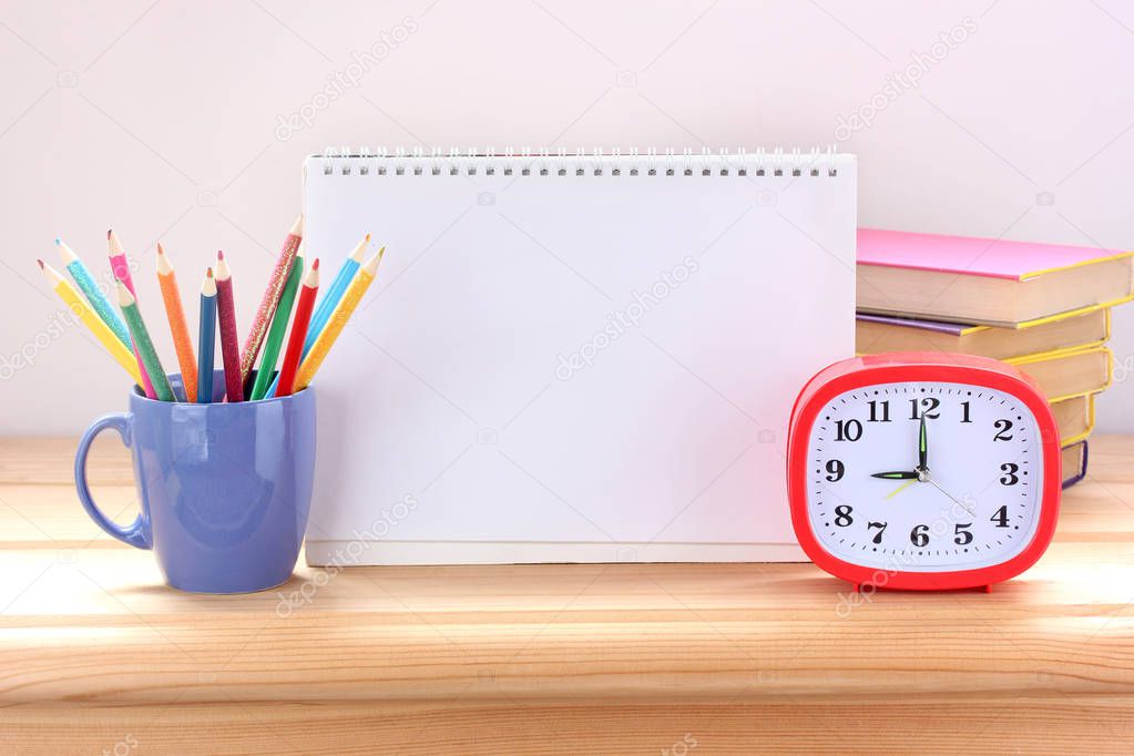 Still life with school supplies on the Desk: alarm clock, textbo