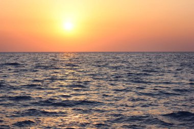 dalgalar ile deniz üzerinde gün batımı.