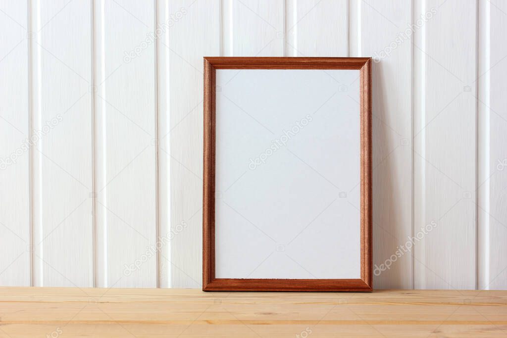 empty wooden frame on the table on the background of a white wall made of boards. mockup, scene creator.