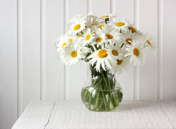 テーブルの上のデイジーの花束 薄い背景にリネンのテーブルクロスにガラス瓶の花 カモミール — ストック写真