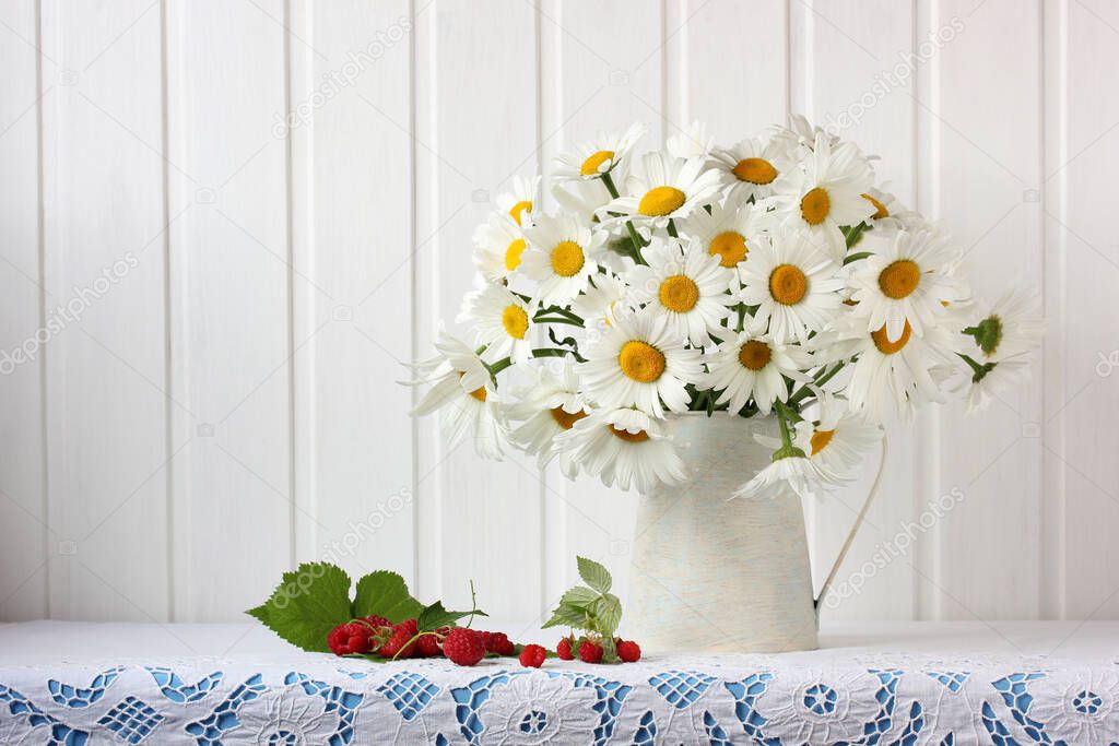 Bouquet of garden daisies and raspberries on the table with a lace tablecloth. Flowers in a jar and berries on a light background.