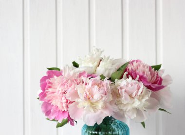 Beyaz tahta arka planında bir buket ışık ve parlak pembe şakayıklar, seçici odaklanma. Bahçe çiçekleri Boşluğu kopyala.