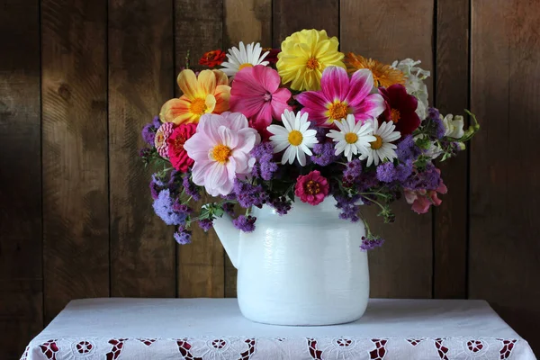 テーブルの上のティーポットの庭の花の花束レーステーブルクロス 暗い静物画 — ストック写真