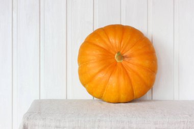 Masanın üzerinde açık arkaplanda turuncu bir balkabağı. bütün bir sebze.