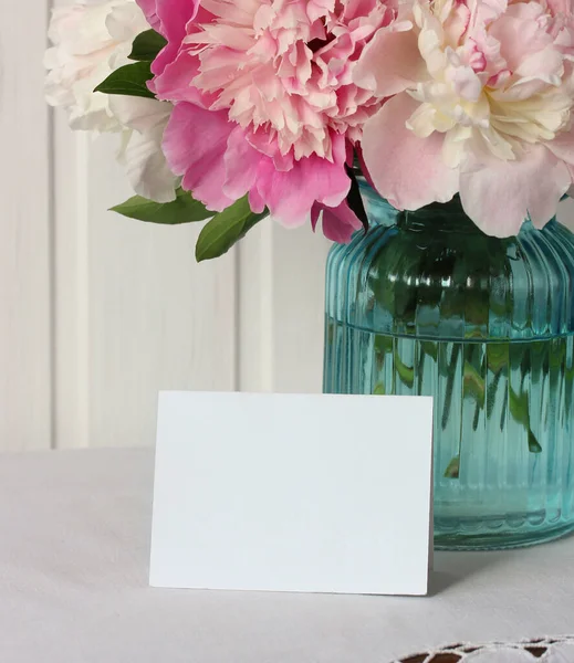 テーブルの上にピンクの牡丹と白いカードの花束 テキストのためのスペース モックアップシーンクリエイター — ストック写真
