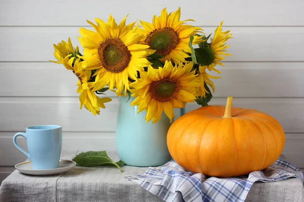 light still life with a bouquet of sunflowers and a pumpkin on the table. harvest, abundance. rustic interior.