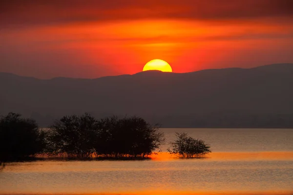 Silhouette Ηλιοβασίλεμα Πίσω Από Την Αντανάκλαση Του Βουνού Στο Νερό — Φωτογραφία Αρχείου