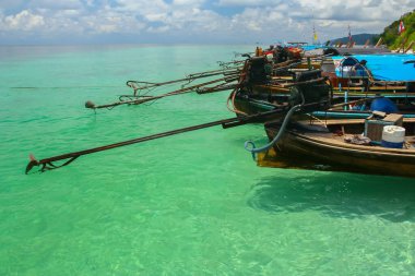 Tayland 'ın güneyindeki berrak gökyüzünün altında uzun bir tekne yüzüyor.