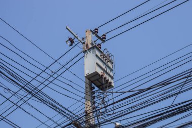 Açık gökyüzü arkaplanına sahip karmaşık kablo kayışlı elektrik direği