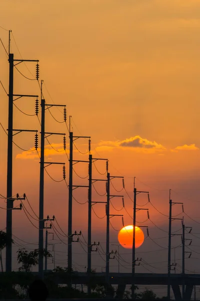 Günbatımı arkaplanının önündeki elektrik direği renkli gökyüzünün altında