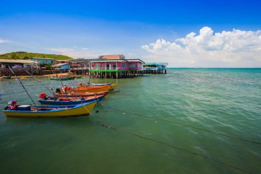 Açık mavi gökyüzünün altında yaz zamanı bulutlu olan renkli uzun tekne parkı.
