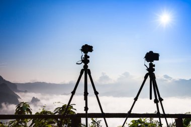DSLR kameraları, Tayland 'ın kuzeyinde yer alan kış mevsiminin erken saatlerinde dağın tepesindeki bulutlu beyaz manzara manzarasının önünde duruyorlar.