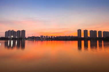 Bir apartman dairesi, gün batımında renkli gökyüzünün altındaki suyun yansımasıdır. Arina Bangkok Tayland 'a çarpma zamanı.