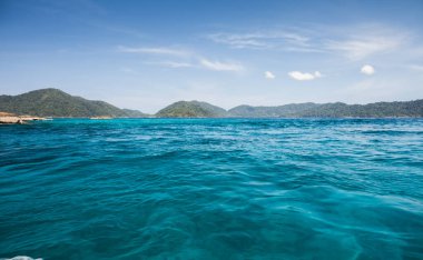 Berrak gökyüzünün altında, tropikana 'nın güneyinde okyanusta dağ altyapısı olan beyaz kumsal.