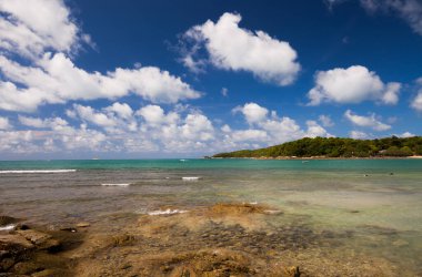 Berrak gökyüzünün altında, tropikana 'nın güneyinde okyanusta dağ altyapısı olan beyaz kumsal.