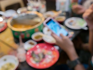 Bir restoranın masasında çeşit çeşit yemek yiyen insanların bulanık görüntüsü.
