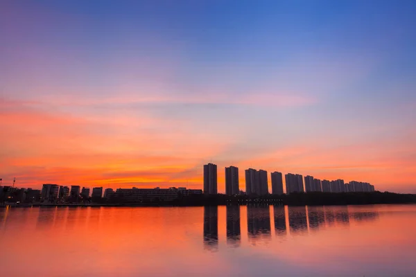 Bir apartman dairesi, gün batımında renkli gökyüzünün altındaki suyun yansımasıdır. Arina Bangkok Tayland 'a çarpma zamanı.