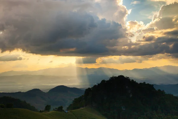Günbatımı, Tayland 'ın kuzeyinde bulutlu gökyüzünün arkasındaki dağa doğru gölgeleniyor.