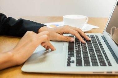 İş adamları masaya koydukları gümüş renkli dizüstü bilgisayarda el yazısı yazıyorlar.