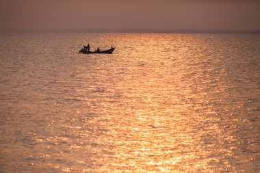 Tayland 'ın doğusundaki Chonburi bölgesinde gün batımında renkli gökyüzünün altında bir tekne yüzüyor.