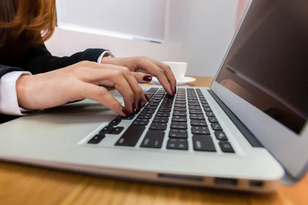 Business people are hand typing on silver color laptop computer put on table