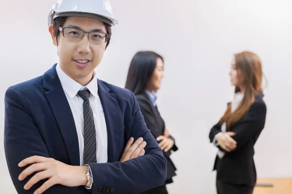 Young business man wear black suit and white helmet standing with background of young business lady