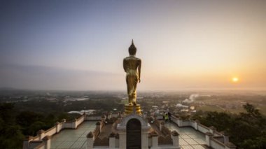 Altın Buda heykeli, Wat Phrathat Khao Noi Tapınağı, Amphoe Mueang, Nan, Tayland 'da gündoğumu zamanlaması konumu olan renkli gökyüzünün önünde duruyor.
