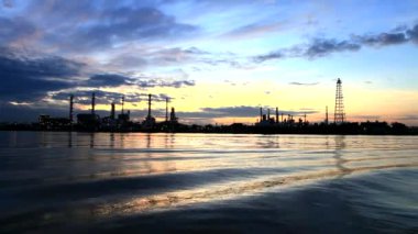 Petrol rafinerisi ve ulaşım denizciliği sabahın erken saatlerinde Bangkok Tayland 'da gün doğumunun renkli gökyüzü altında Chaopraya nehrine yansıyor.
