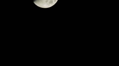 Gece vakti karanlık gökyüzünde hızla hareket eden bir ay bulutlu bir bulutun yanından geçer.