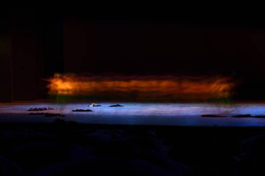 Siyah arka plana karşı sahnede dans eden bir grup insan. 