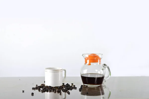 Coffee cup and coffee jug with coffee seed on a table against white background
