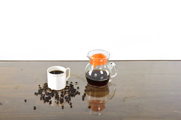 Coffee cup and coffee jug with coffee seed on a table against white background