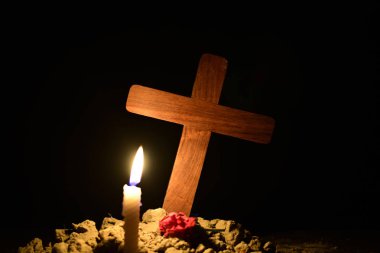 Siyah arka plana karşı bir mezarlıkta ISA haç altında yanan mum.