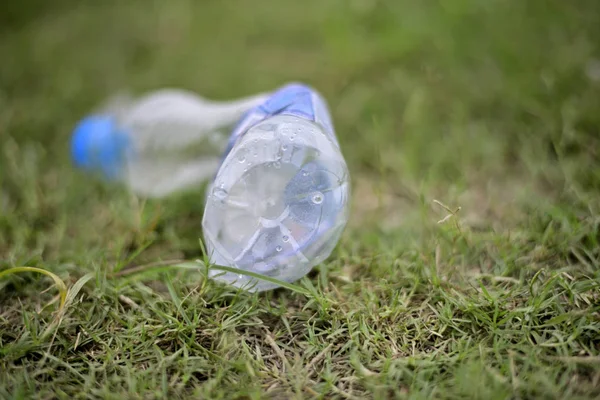 Discarded plastic water bottle on green grass field.