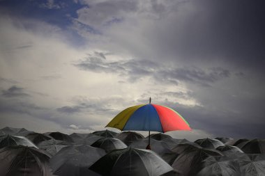 Yağmur mevsiminde birçok siyah şemsiye üzerinde renkli şemsiye.