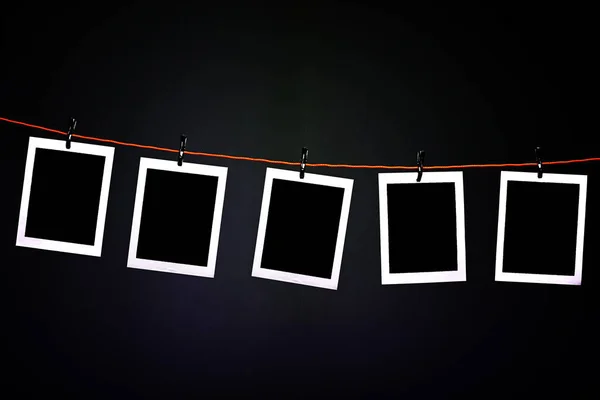 Blank Polaroid photographs hanging on a rope in photography dark room