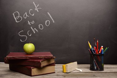 Kitaplar ve eğitim malzemeleri sınıftaki ahşap masada.