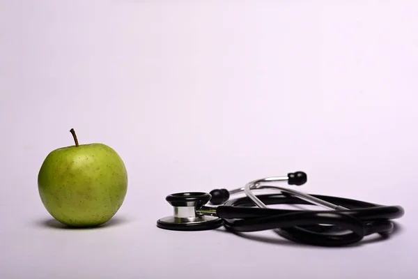 灰色の背景に隔離された緑のリンゴと聴診器 — ストック写真
