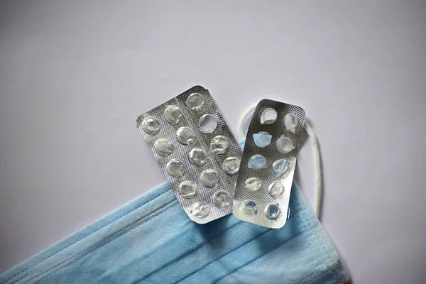 surgical mask and empty tablet capsule script on gray background