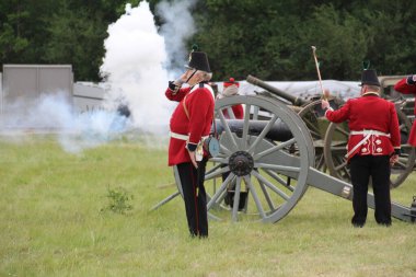 Waterlooville, İngiltere - 26 Mayıs 2019: 19. yüzyıldan kalma taklit bir topun ateşlendiğini gösteren kostüm içindeki silah ekibi.