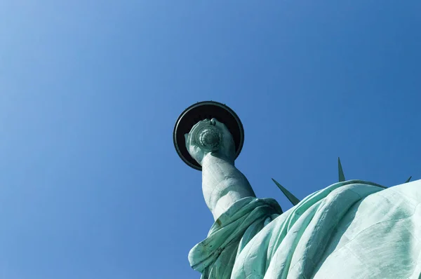 Statue of Liberty fragment, seen from a low angle, against blue clear sky, on the Liberty Island of New York, USA