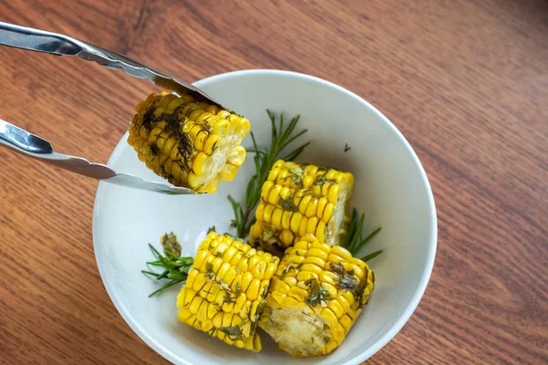 Cucinato in forno mais con erbe su fondo di legno in ciotola bianca, cottura pannocchie di mais a mano chef, vista dall'alto — Foto Stock